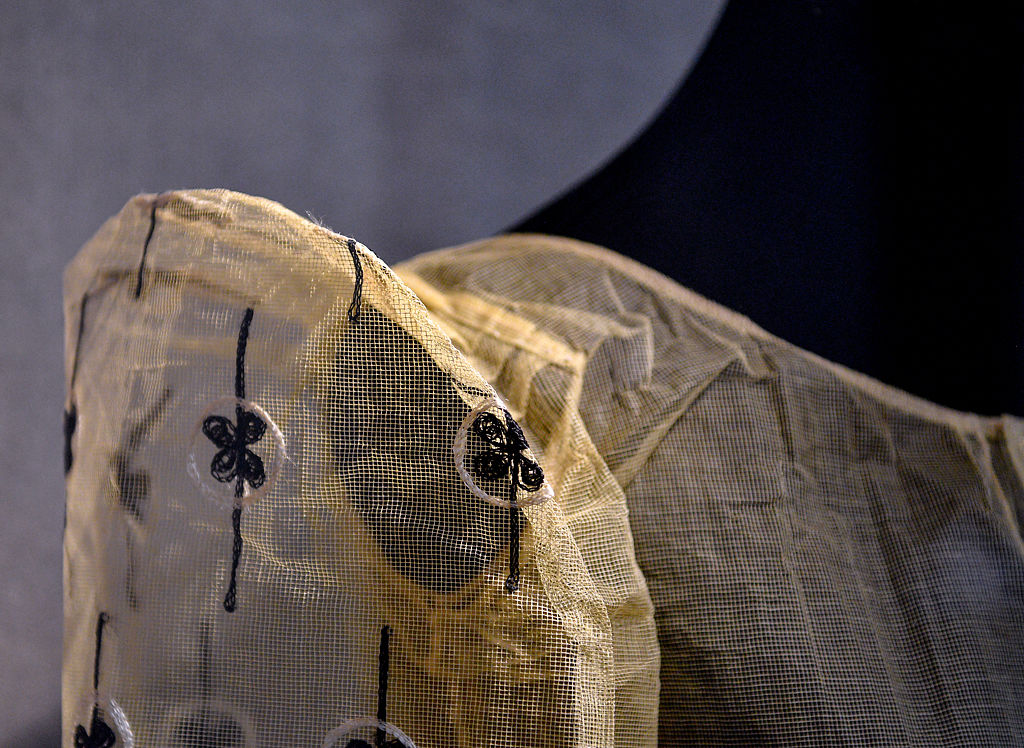 A garment made from pineapple leaves sits behind glass